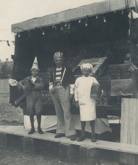Drie personen voor de koekkraam op de kermis