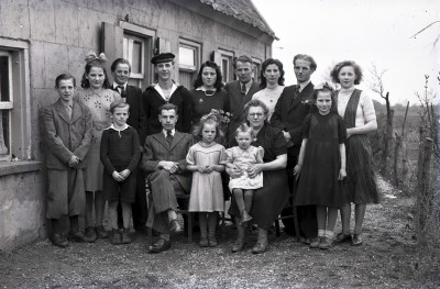 Groepsfoto van de familie Morlog voor hun boerderij in Grave. In 1952 is bijna de hele familie geëmigreerd naar Canada.