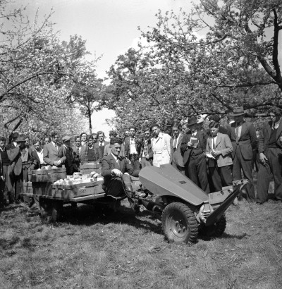 Strak in het pak, haar in de krul en kijken naar een motormaaier met aanhanger. Liempde 1949