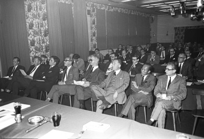 Verschillende mannen genieten van een pijp, sigaar of sigaret tijdens een vergadering. Vught, 1967