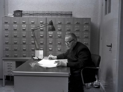 Roken tijdens het werk op kantoor. Op het bureau staat een asbak. Grave, ?