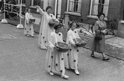 Meisjes strooien bloemen uit manden, tijdens een processie. Grave, ?