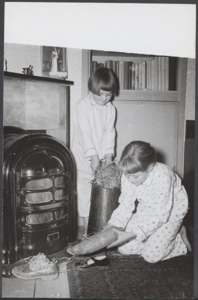 Twee meisjes zetten hun schoen bij de kachel, met een wortel en hooi voor het paard. Plaats onbekend, 1953