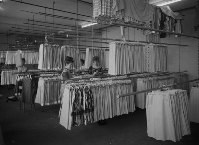 Rekken vol kleding controleren, Geffen 1964 (foto: Fotopersbureau Het Zuiden, collectie BHIC nr. 1636-000297)