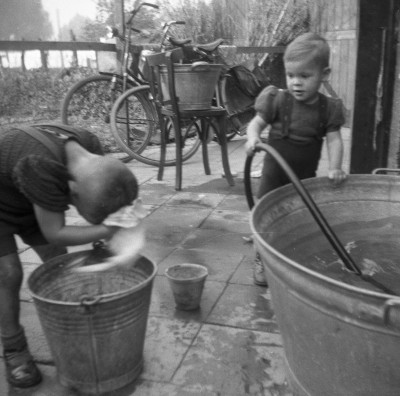 Spelen met water bij de wastobbe en poetsemmer. Sint-Oedenrode, ca. 1950