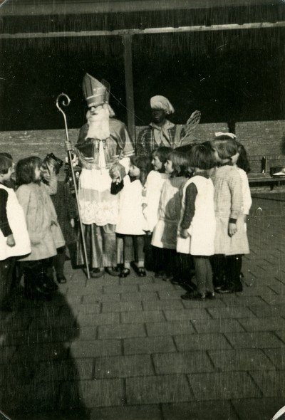 Sint met een wat vervilte baard bij een groepje kinderen. Tilburg, 1934