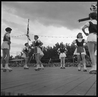 Demonstratie rolschaatsen op het Udens Kersenhof met op de achtergrond vogelverschrikker Peerke Verschiet, Uden 1954 (foto: J. Schellinx, collectie BHIC nr. 1958-A-000517)