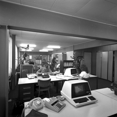 Noodhuisvesting afdeling Financiën van de Blauwe Kei met computer, telefoon met draaischijf en asbak op het bureau, Veghel (foto: Harry van Liempd, collectie BHIC nr. 1915-001896)   